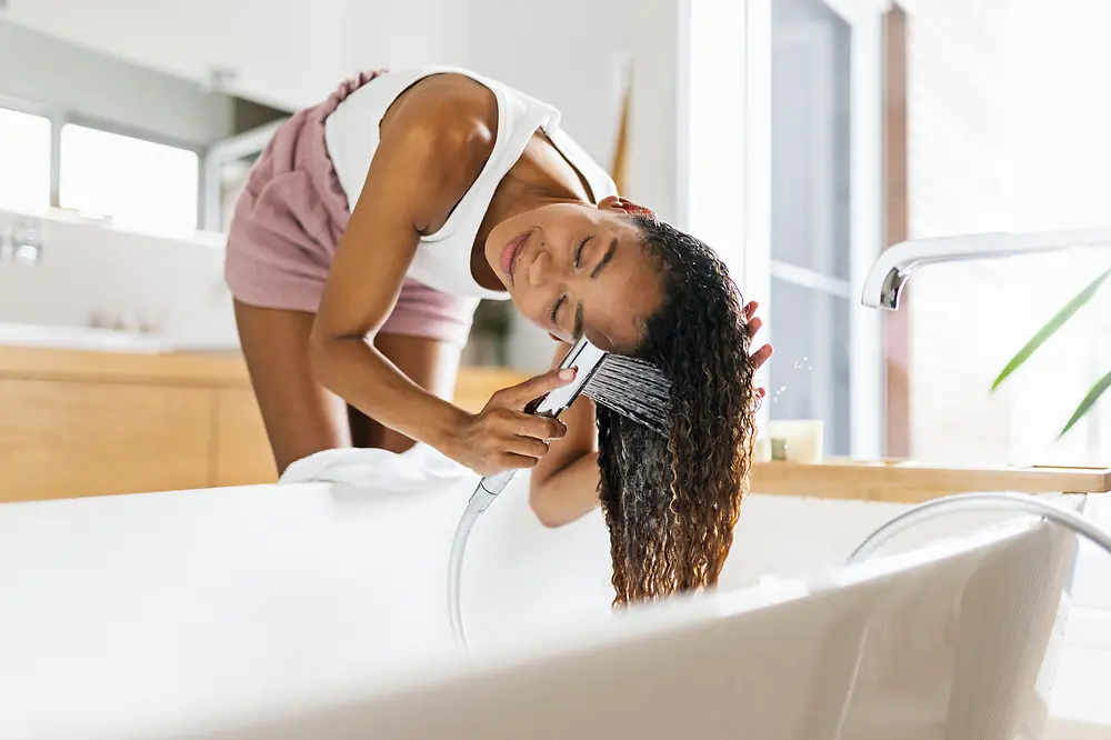 Donna in bagno che si lava i capelli nella vasca