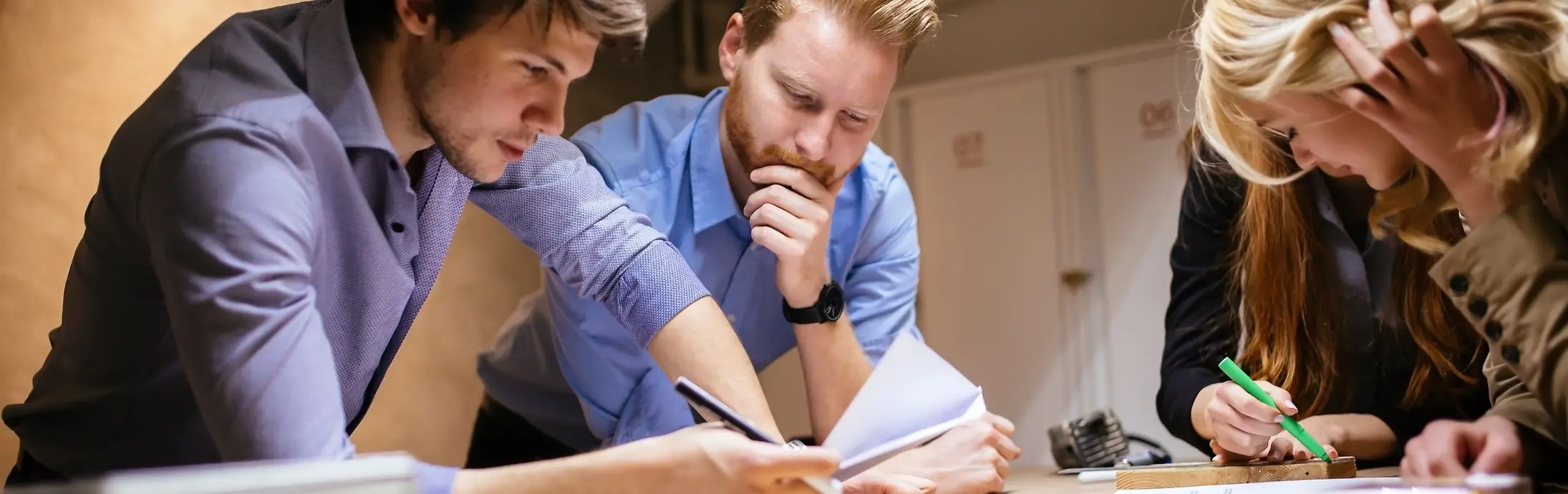 Un gruppo di 4 colleghi appoggiati a un tavolo e che consultano dei documenti