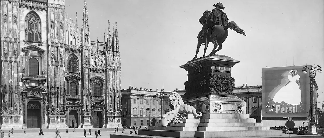 piazza Duomo Milano con statua pubblicità e persone che camminano