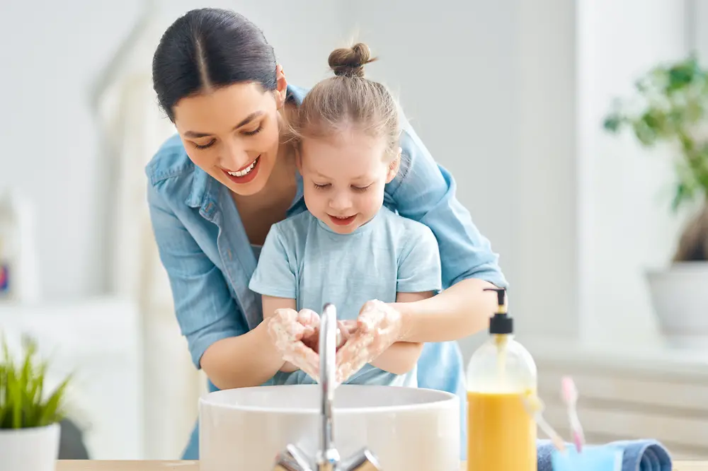 Mamma che aiuta la bambina a lavare le mani